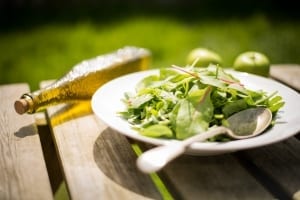 healthy salad on a table outside with bottle of oil